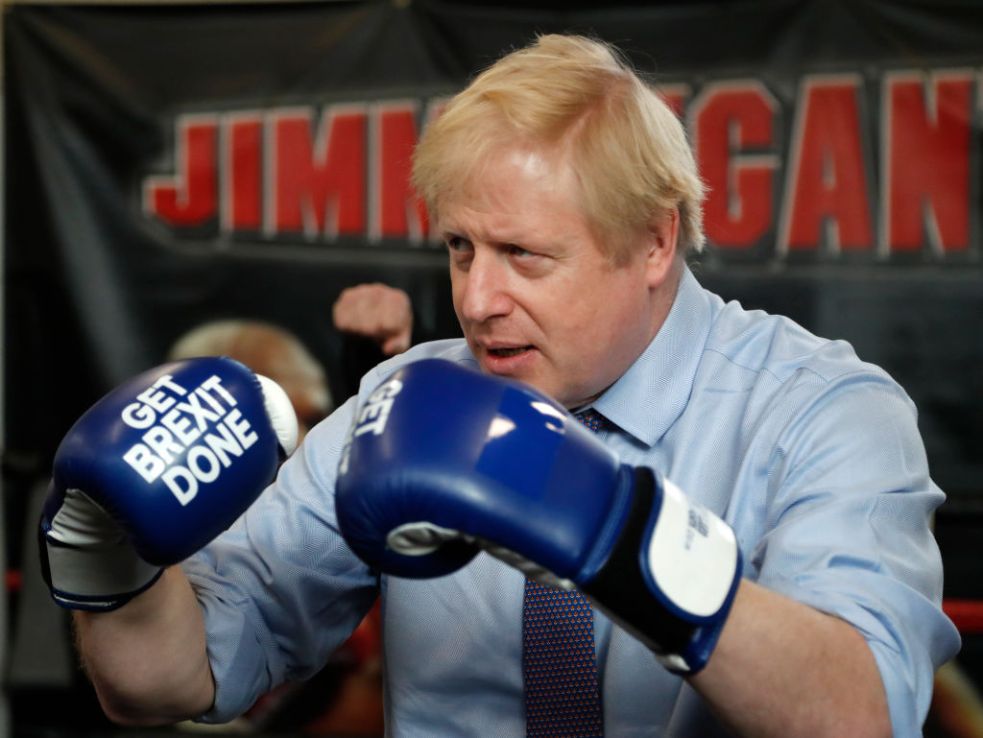 MANCHESTER, ENGLAND - NOVEMBER 19: Britain's Prime Minister Boris Johnson poses for a photo wearing boxing gloves emblazoned with "Get Brexit Done" during a stop in his General Election Campaign trail at Jimmy Egan's Boxing Academy on November 19, 2019 in Manchester, England. Britain goes to the polls on Dec.12. (Photo by Frank Augstein - WPA Pool/Getty Images)