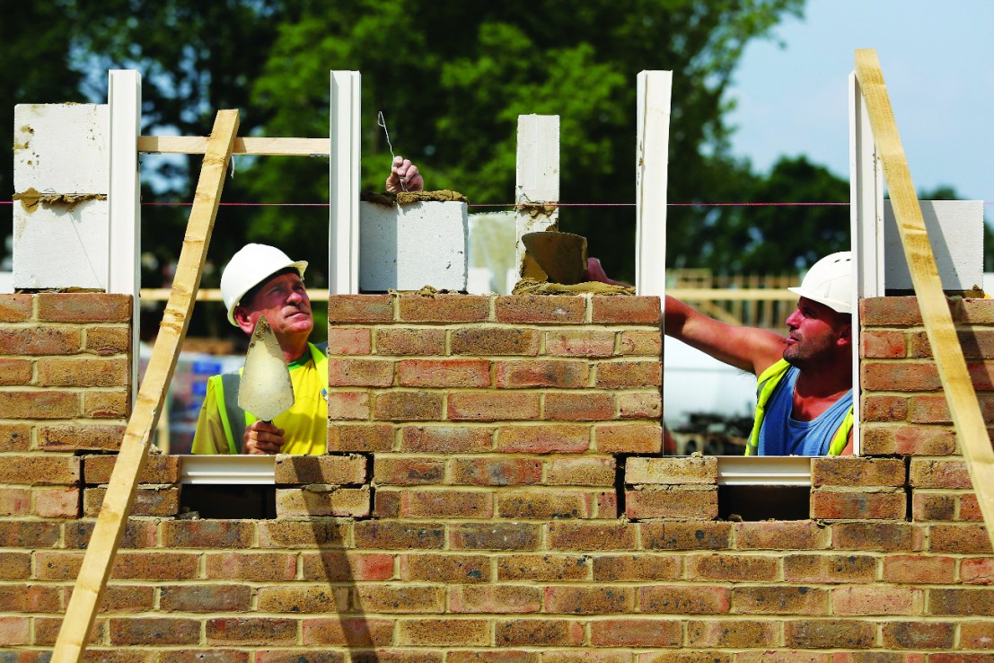 Construction workers lay bricks around window apertures for a new home under construction at a Crest Nicholson Holdings Plc residential housing development  (Photographer: Chris Ratcliffe/Bloomberg via Getty Images)