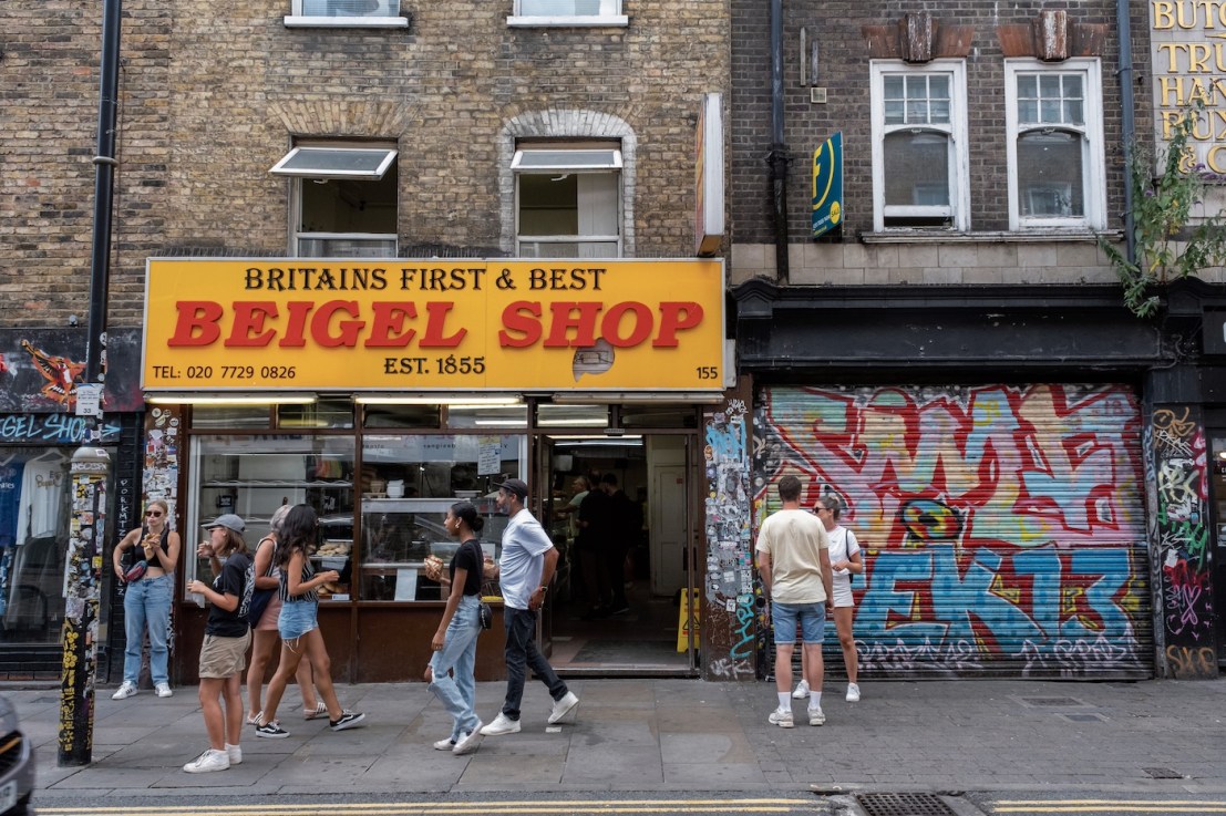 Street scene with customers and local people hanging outside the Beigel Shop on Brick Lane. (photo by Mike Kemp/In Pictures via Getty Images)