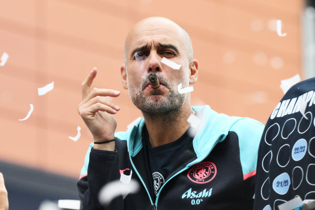 MANCHESTER, ENGLAND - MAY 26: Pep Guardiola, Manager of Manchester City, looks on as he smokes a cigar whilst on the Open Top Bus during the Manchester City trophy parade on May 26, 2024 in Manchester, England. (Photo by Ben Roberts Photo/Getty Images)